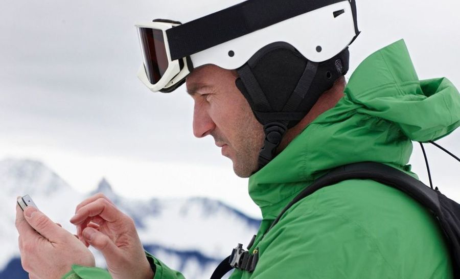 Esquiador mirando un teléfono móvil en pistas