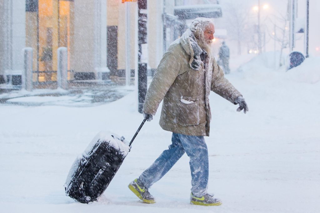 Turistas arrastrando la maleta sobre la nieve