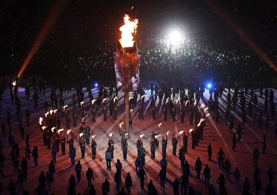 Fotografía de la llama Olímpica en la ceremonia inaugural con todos alrededor de la misma 