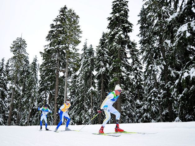 Fotografía de tres esquiadores de la categoría de pie en carrera de esquí de fondo