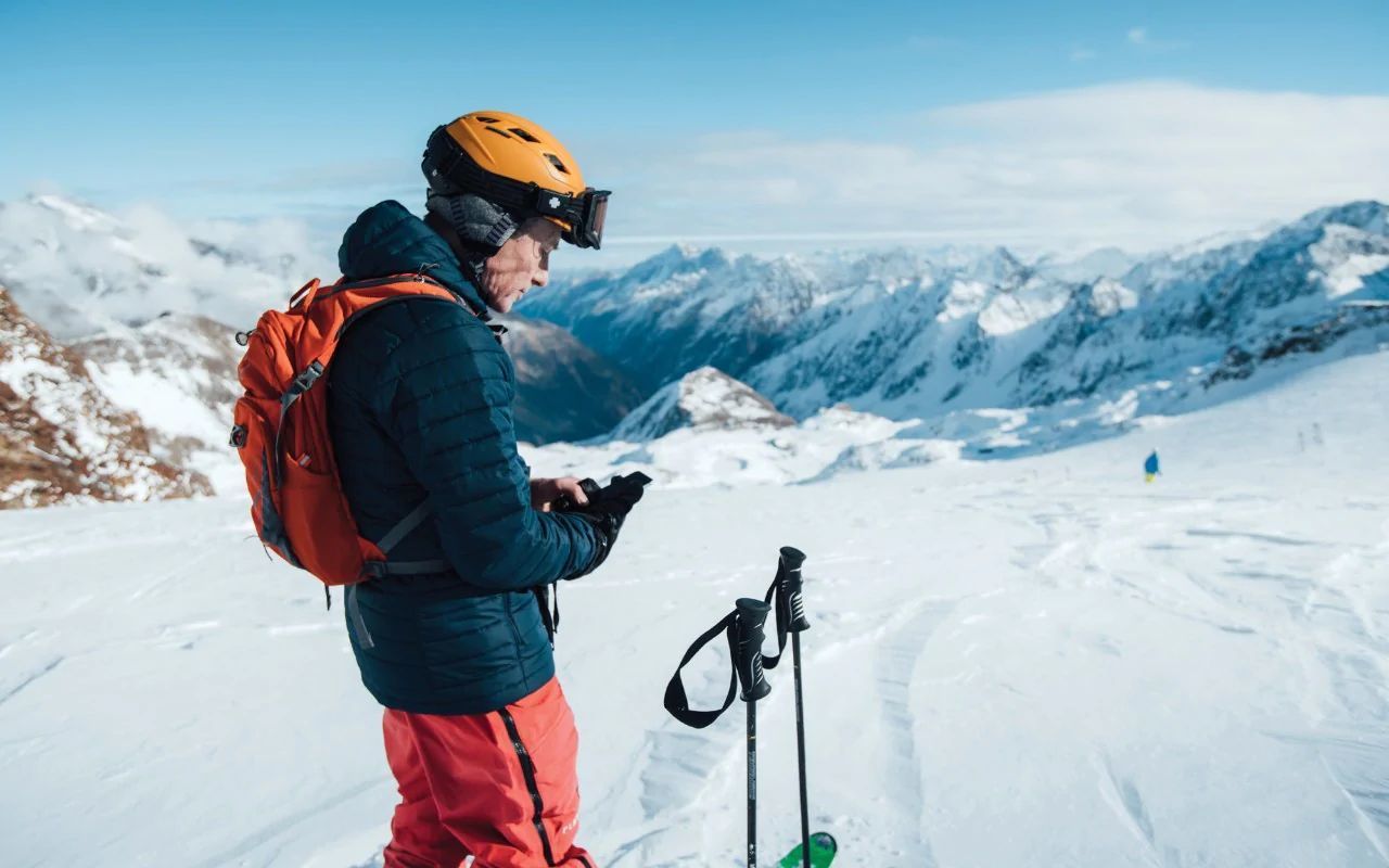 Esquiador con móvil en la mano mirando App