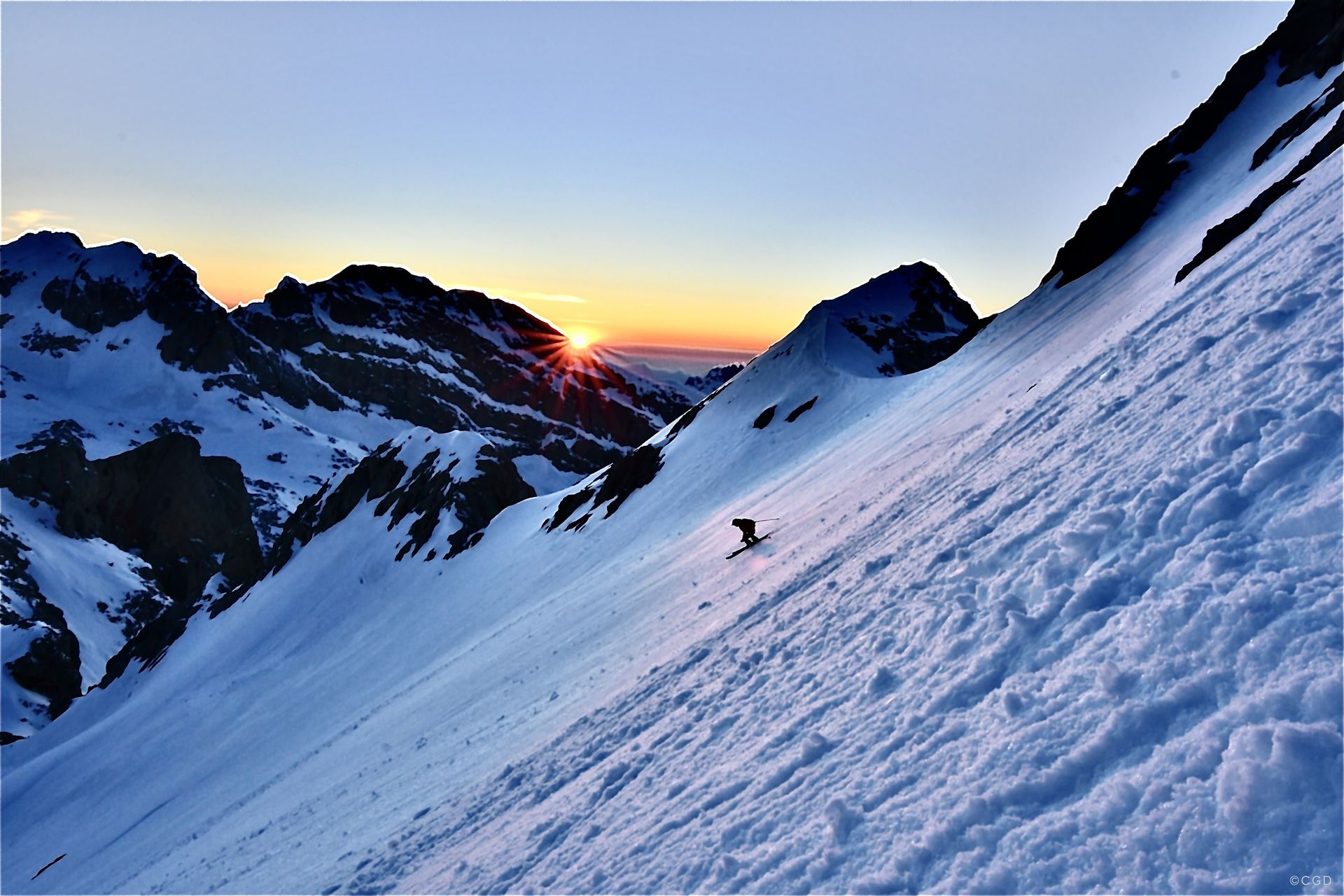 Pepín Román esquiando desde la cumbre del Tesorero con las últimas luces del dia iluminando las montañas mas altas de Cantabria, en el Macizo Central de los Picos de Europa.