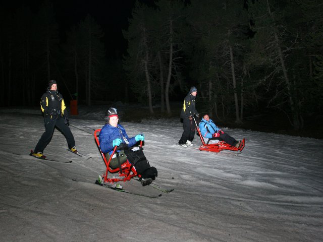Fotografía de esquiadores discapacitados en pista por la noche