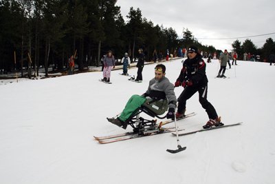 Fotografía de un monitor de esquí adaptado con un alumno en dual esquí